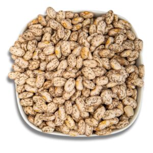 A close-up of dry pinto beans in a white bowl, showcasing their natural speckled texture.